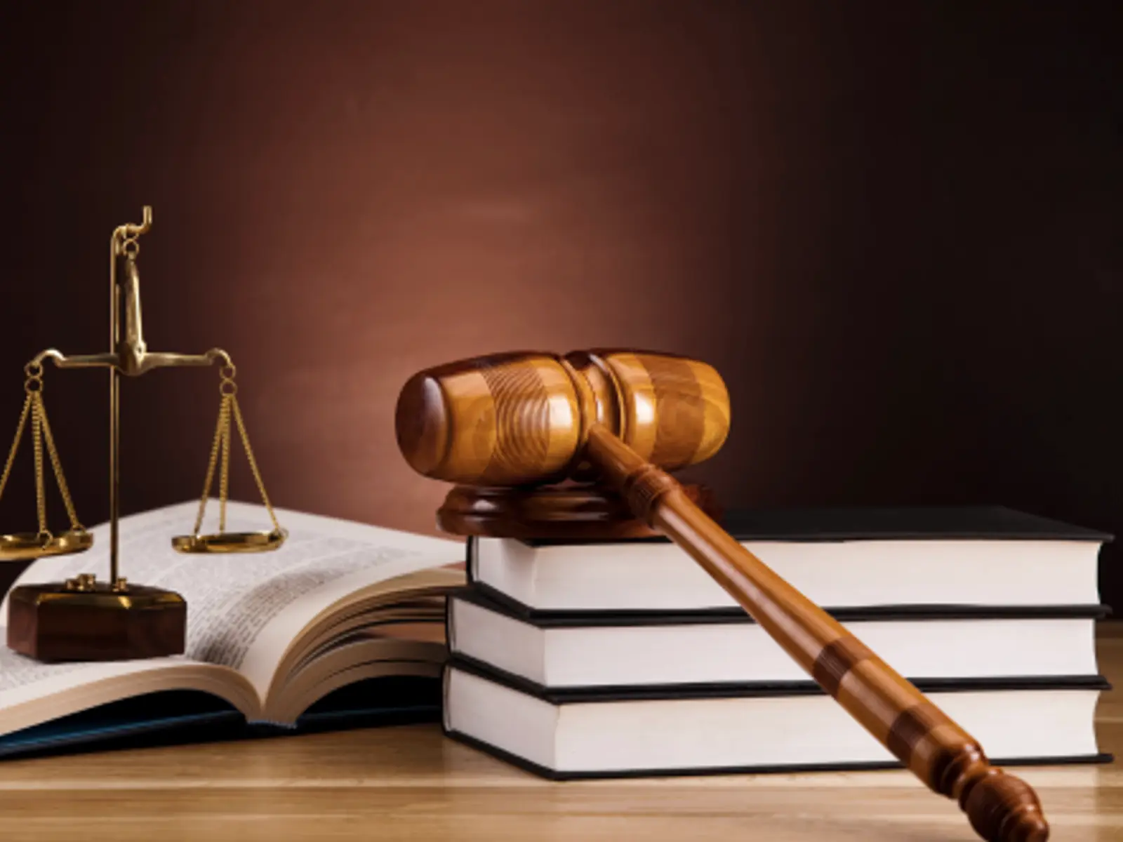 Mazo judicial, balanza de la justicia y libros de derecho sobre una mesa, símbolos de la defensa legal.